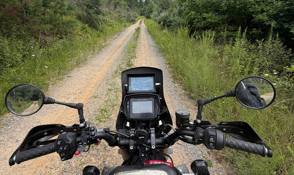 The view from the seat of my FTR on a gravel two-track, with the nav tower, risers and hand guards.