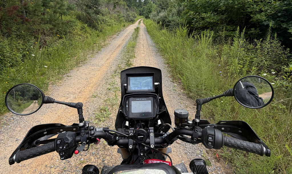 The view from the seat of my FTR on a gravel two-track, with the nav tower, risers and hand guards.