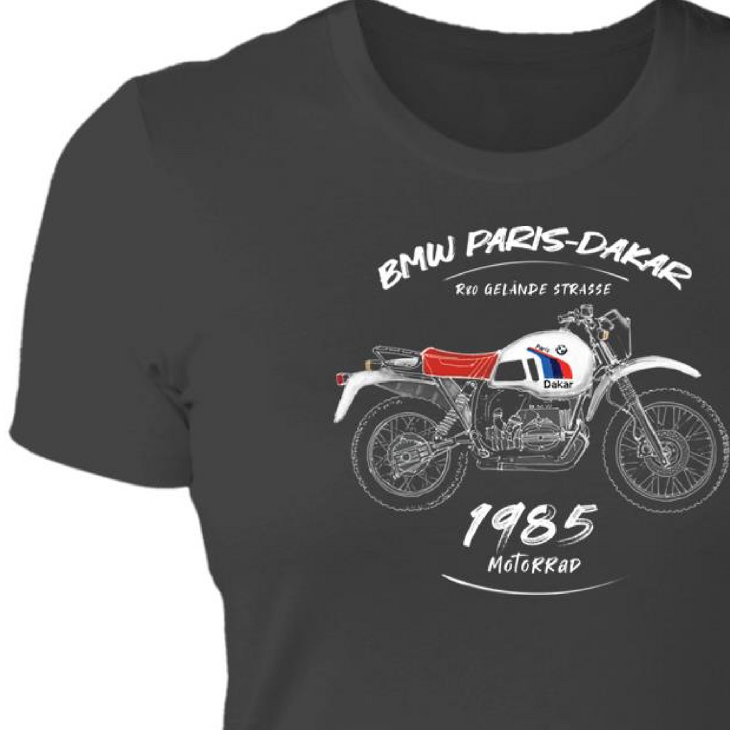 From Cannonball Adventure, this women's T-shirt features a hand-sketched design of a BMW adventure bike R80GS. This motorcycle was created for the 1985 Paris-Dakar Rally. Beautiful art details of motorcycle and text that includes "BMW Paris-Dakar", "Gelande Strasse" and "1985". This t-shirt in dark grey and made of 100% cotton.